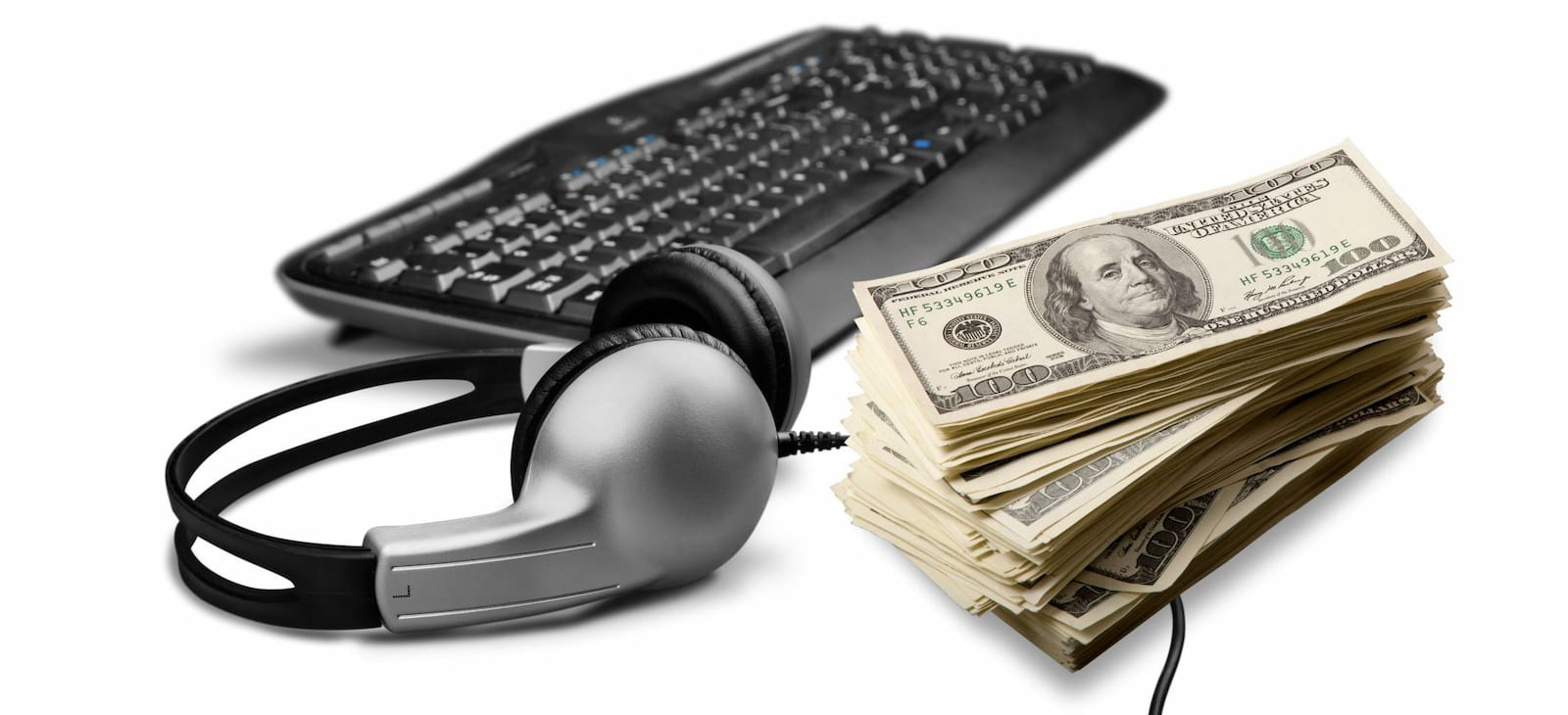 A stack of cash beside the headphones and keyboard