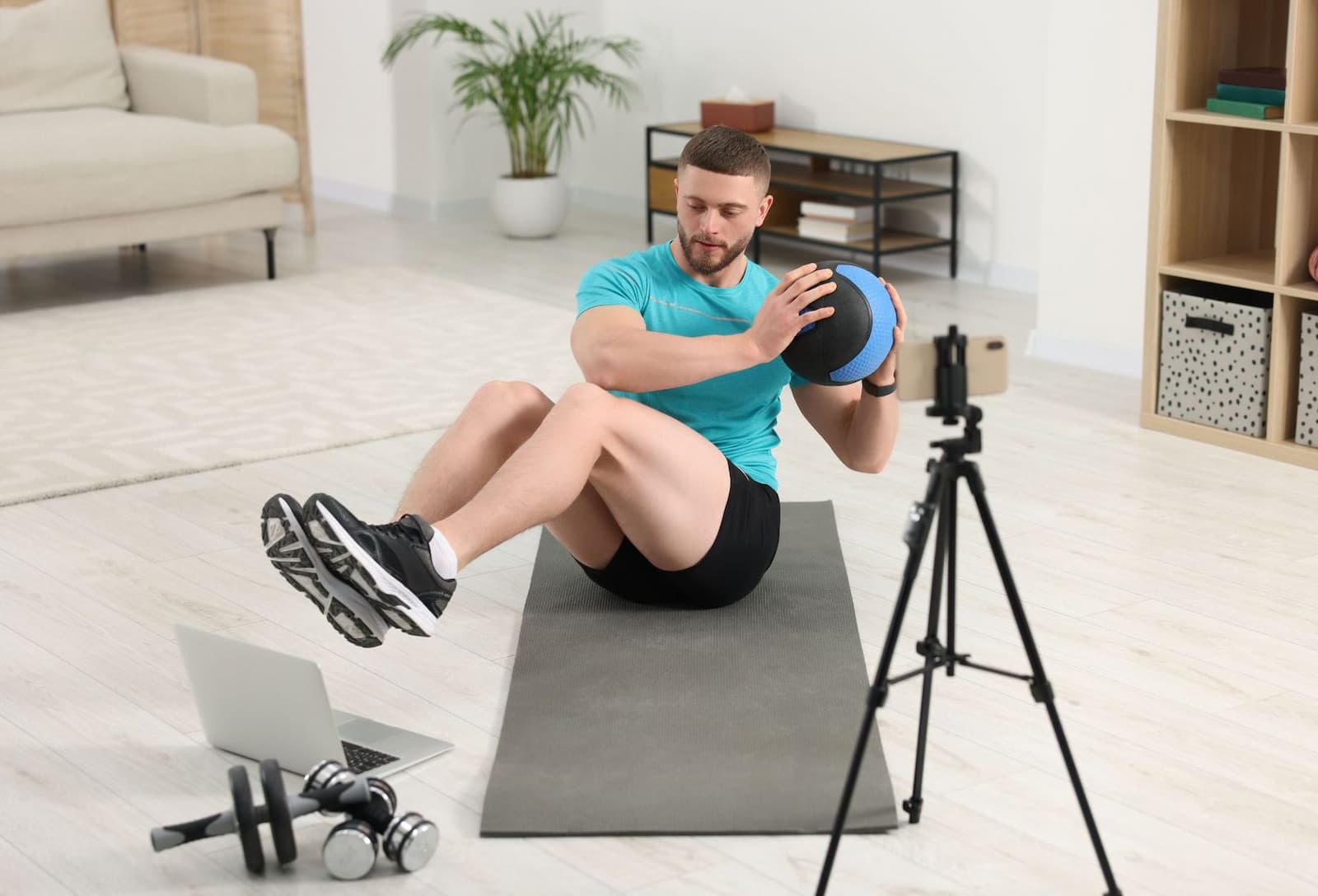 A man working out in his living room in front of a camera and laptop